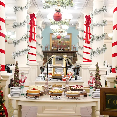 Holiday buffet with a Christmas dessert bar, twinkling lights, and red-and-white striped ribbons in a decorated hall.