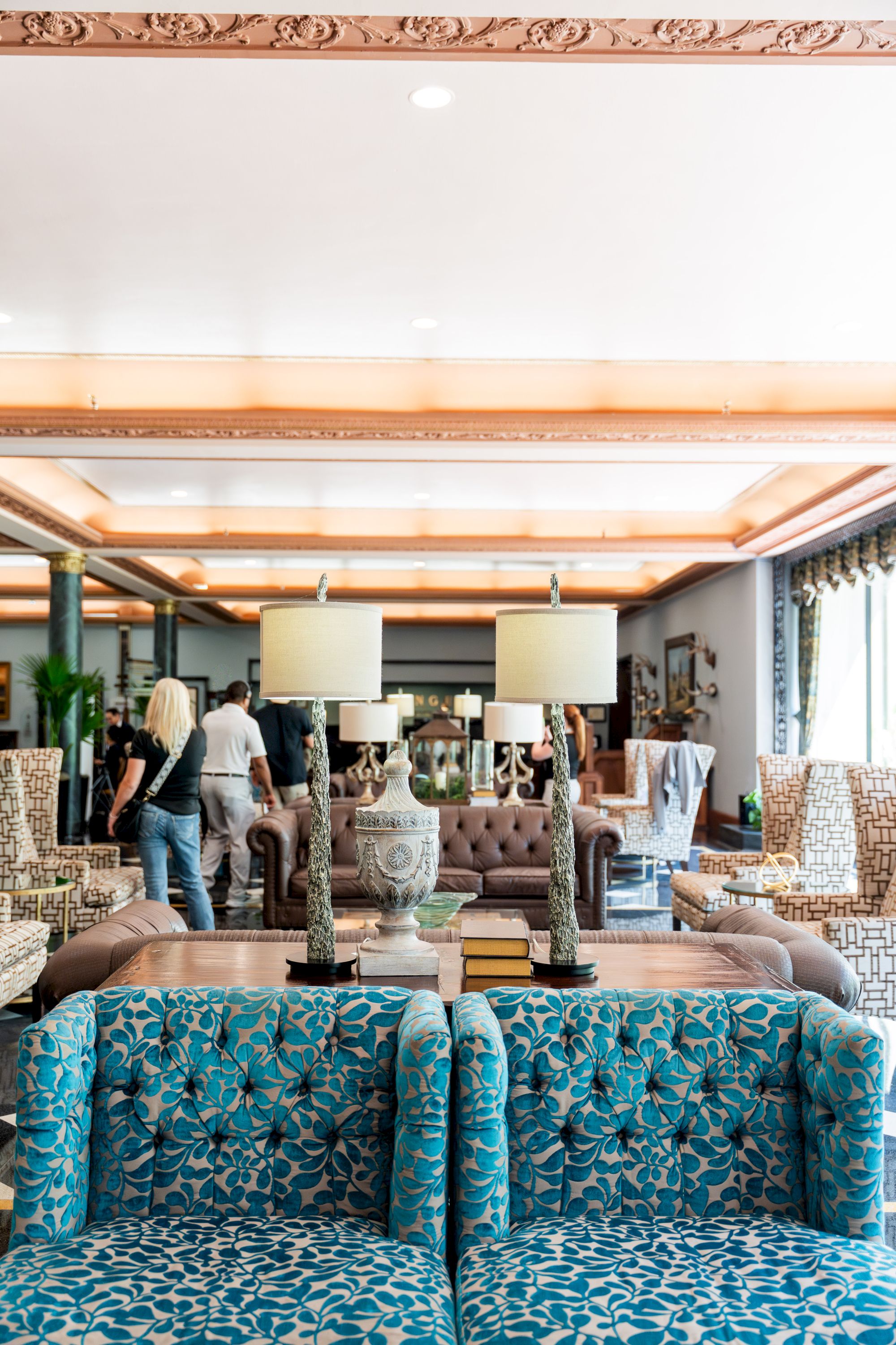 A chic hotel lobby filled with patterned sofas, tufted chairs, floor lamps, and guests browsing in the stylish lounge area. ending now.