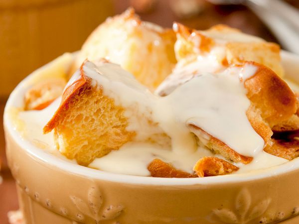 Creamy bread pudding or tiramisu-like dessert topped with whipped cream, served in a decorative bowl.
