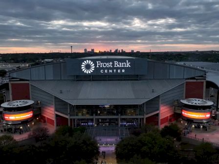 Aerial view of the Frost Bank Center arena at dusk, with the &ldquo;Frost Bank Center&rdquo; sign lit above the building entrance.