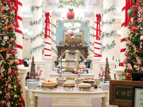 A festive holiday buffet with Christmas garlands, red-and-white striped decor, ornaments, and a serving station in a decorated room.