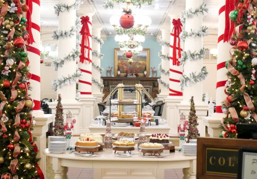 Holiday buffet with a Christmas dessert bar, twinkling lights, and red-and-white striped ribbons in a decorated hall.